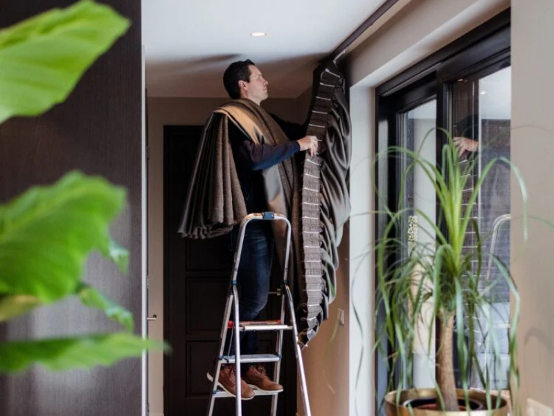Verticale houten wandpanelen op maat achter een vrijstaande kachel in een lichte woonkamer