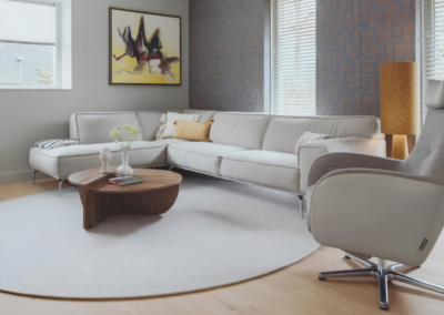 Licht vloerkleed in woonkamer met hoekbank en houten vloer