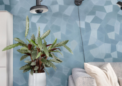 Blauwe grafische behangwand achter bank met plant en wandlamp