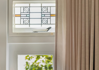 Beige gordijnen naast glas-in-lood raam in klassieke woonkamer