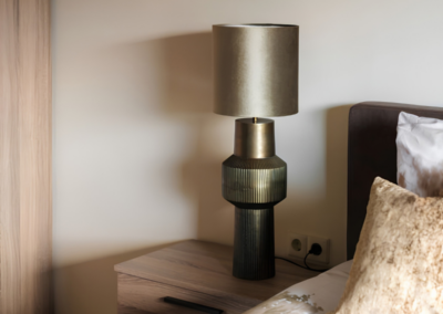 Houtlook nachtkastje met sfeerlamp naast bed in warme slaapkamer