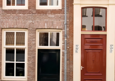 Monumentale gevel met rood geschilderde deur en witte kozijnen