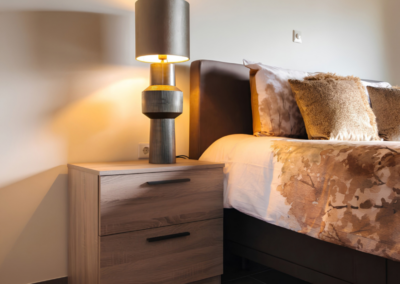 Sfeervolle slaapkamer met brandende bedlamp en houtlook nachtkastje