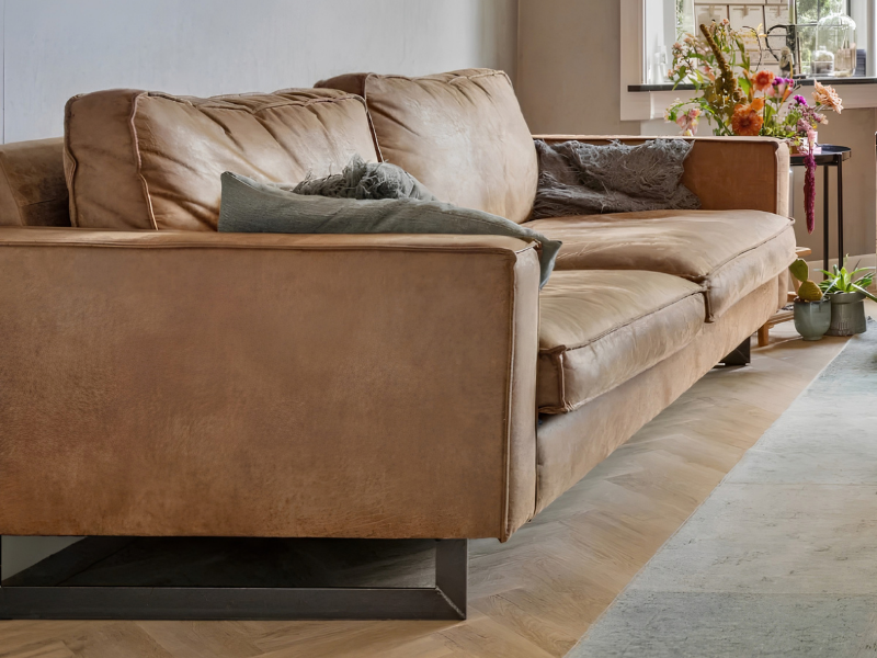 Warme woonkamer met leren bank, visgraat PVC-vloer en vloerkleed