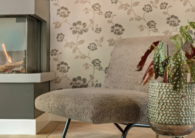 Zithoek met bloemenbehang, haard, fauteuil en kamerplant